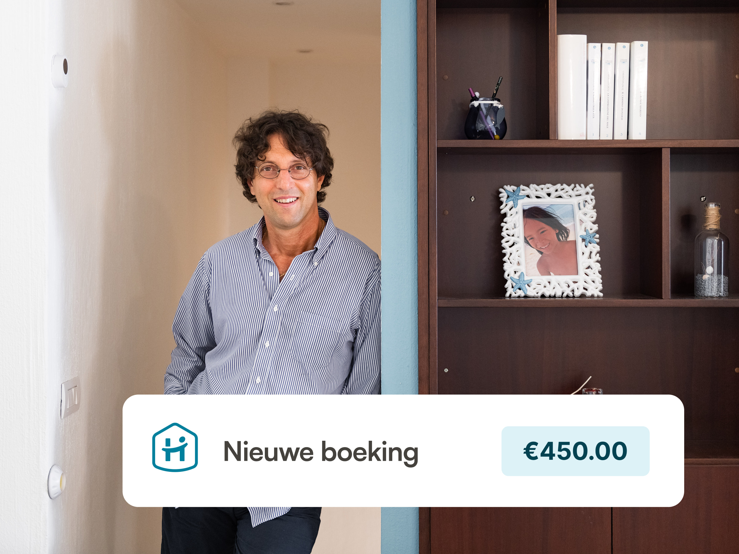 Host standing in his vacation rental, looking happy, next to a nicely decorated shelve