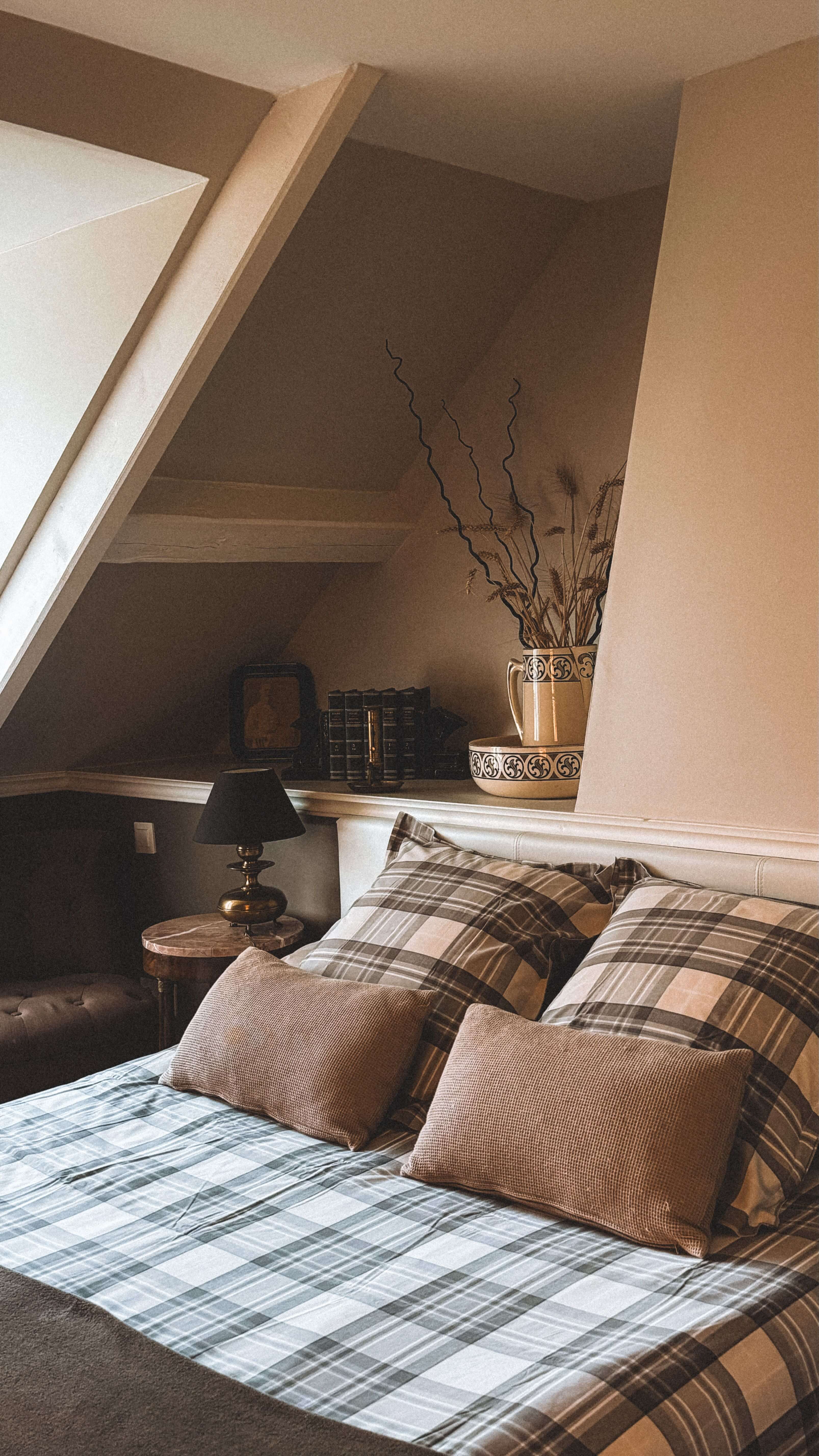 Chambre d'hôtes de charme sous les combles, avec lit à linge à carreaux et décoration rustique traditionnelle