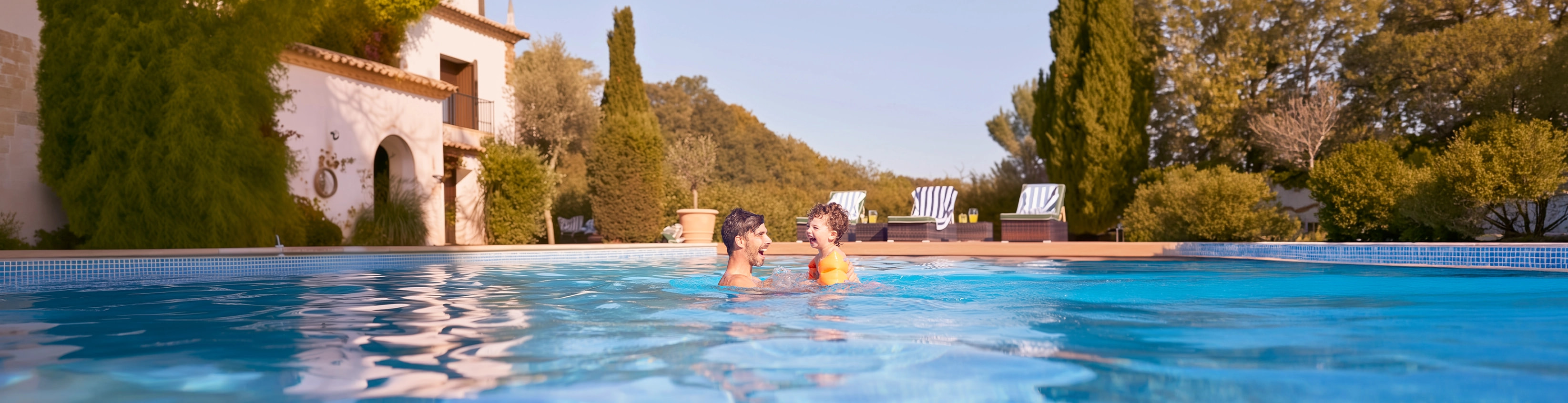 Father and son playing in pool in front of their rural holiday home