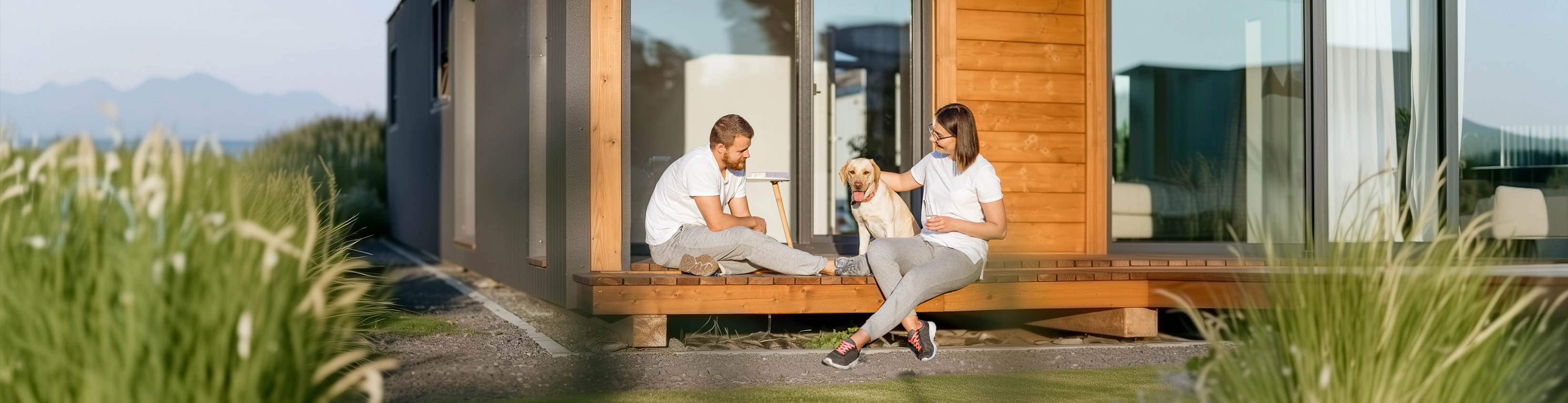 Couple sitting outside of a beach house with their dog