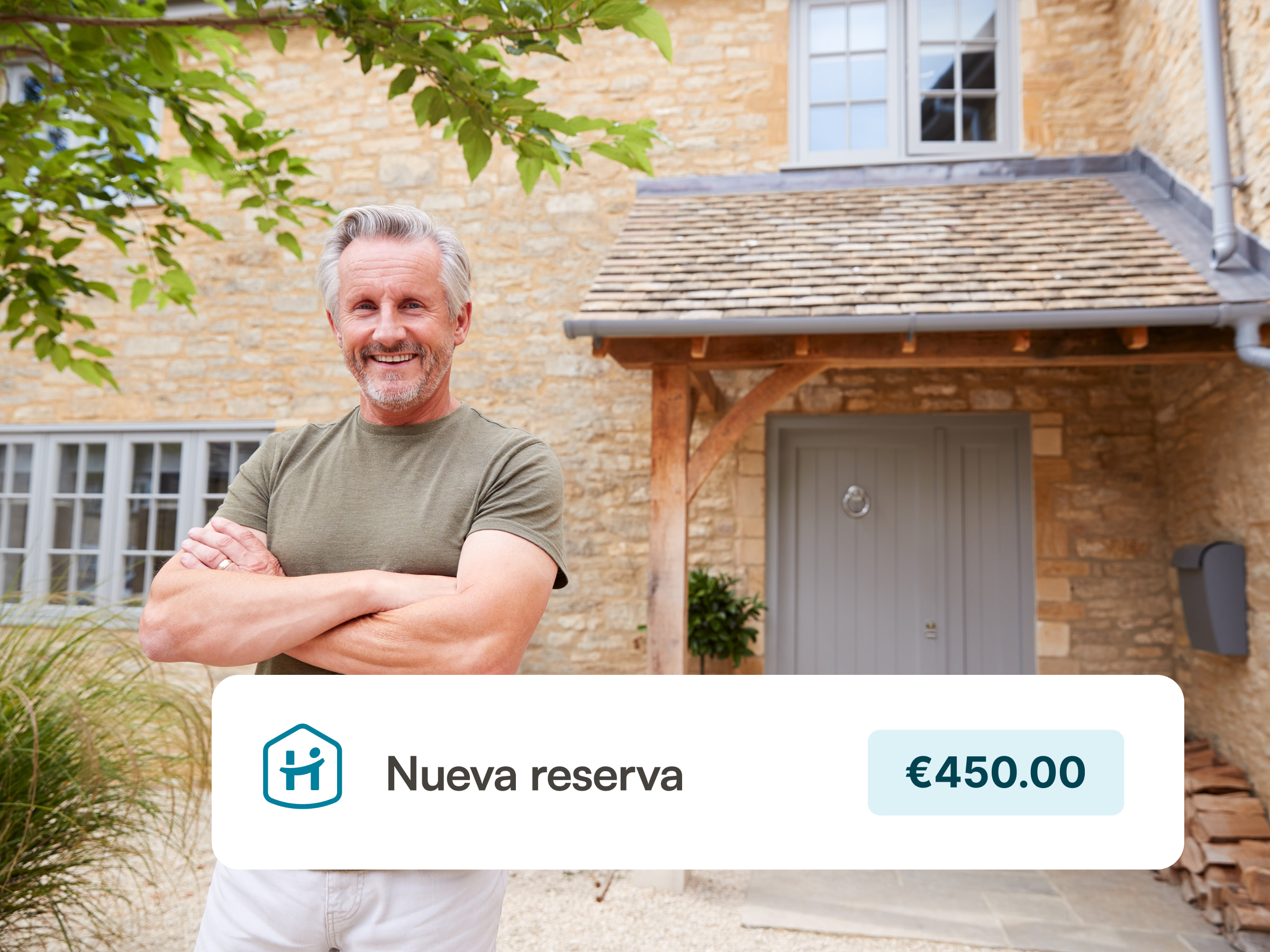 A happy host standing in front of his country home with a stone facade and a tree