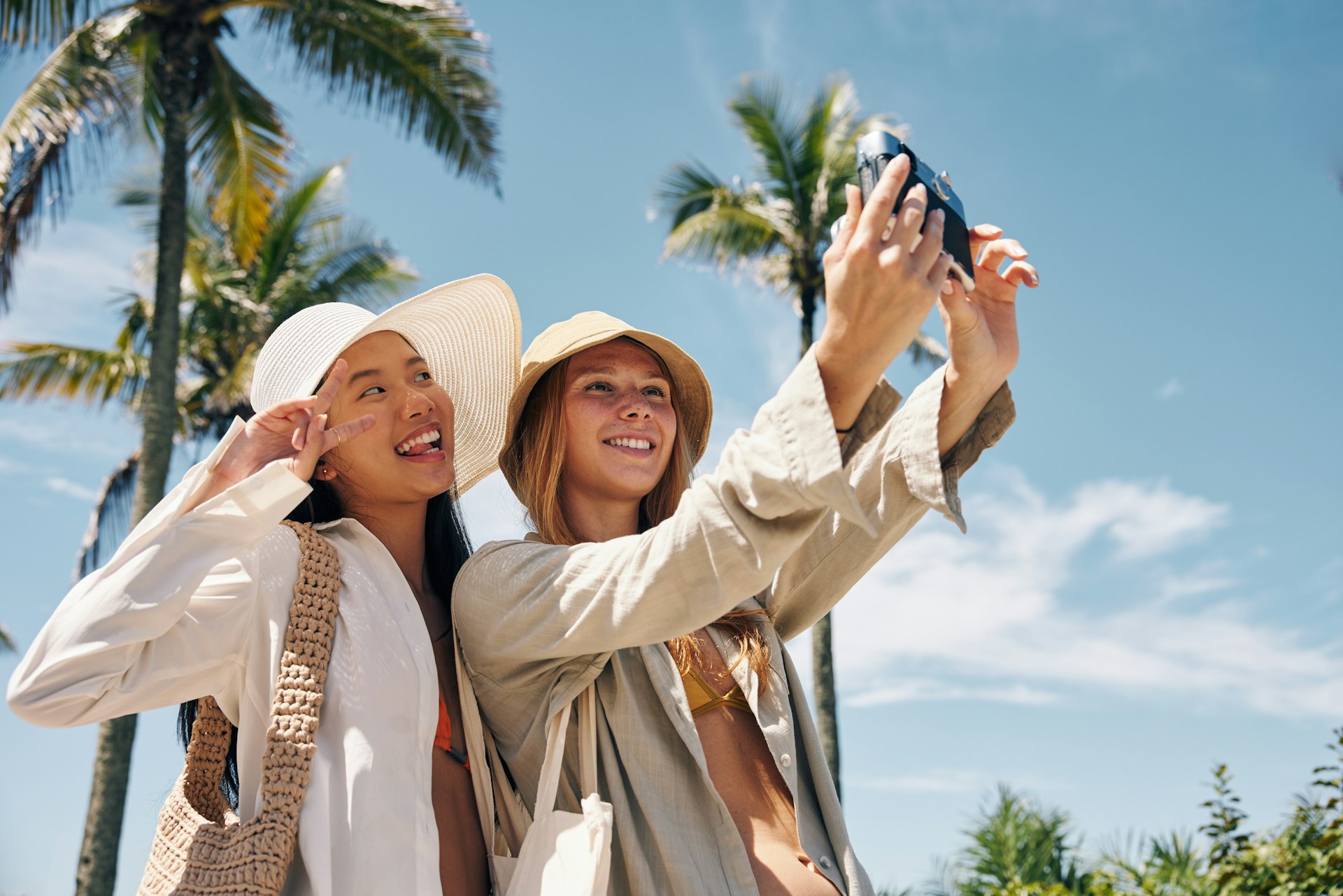 Security deposits for holiday homes: pros and cons Gemini said Two happy travelers take a selfie together under tropical palm trees, capturing the carefree guest experience that hosts aim to protect when they advertise a holiday home with a security deposit.