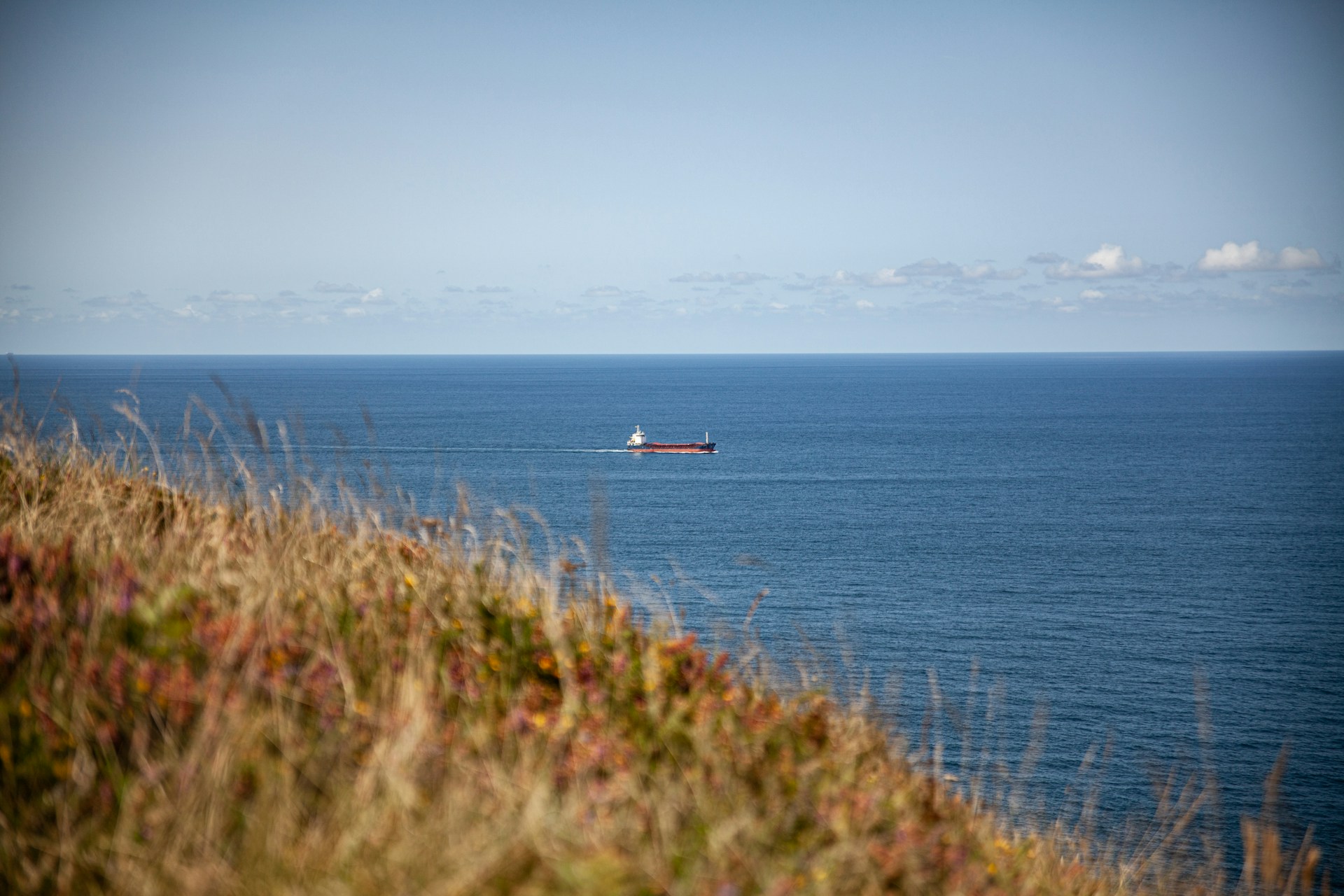 A cargo ship sails across the Cantabrian Sea, symbolizing the coastal charm the Urban Planning Compatibility Report aims to preserve through sustainable tourism.