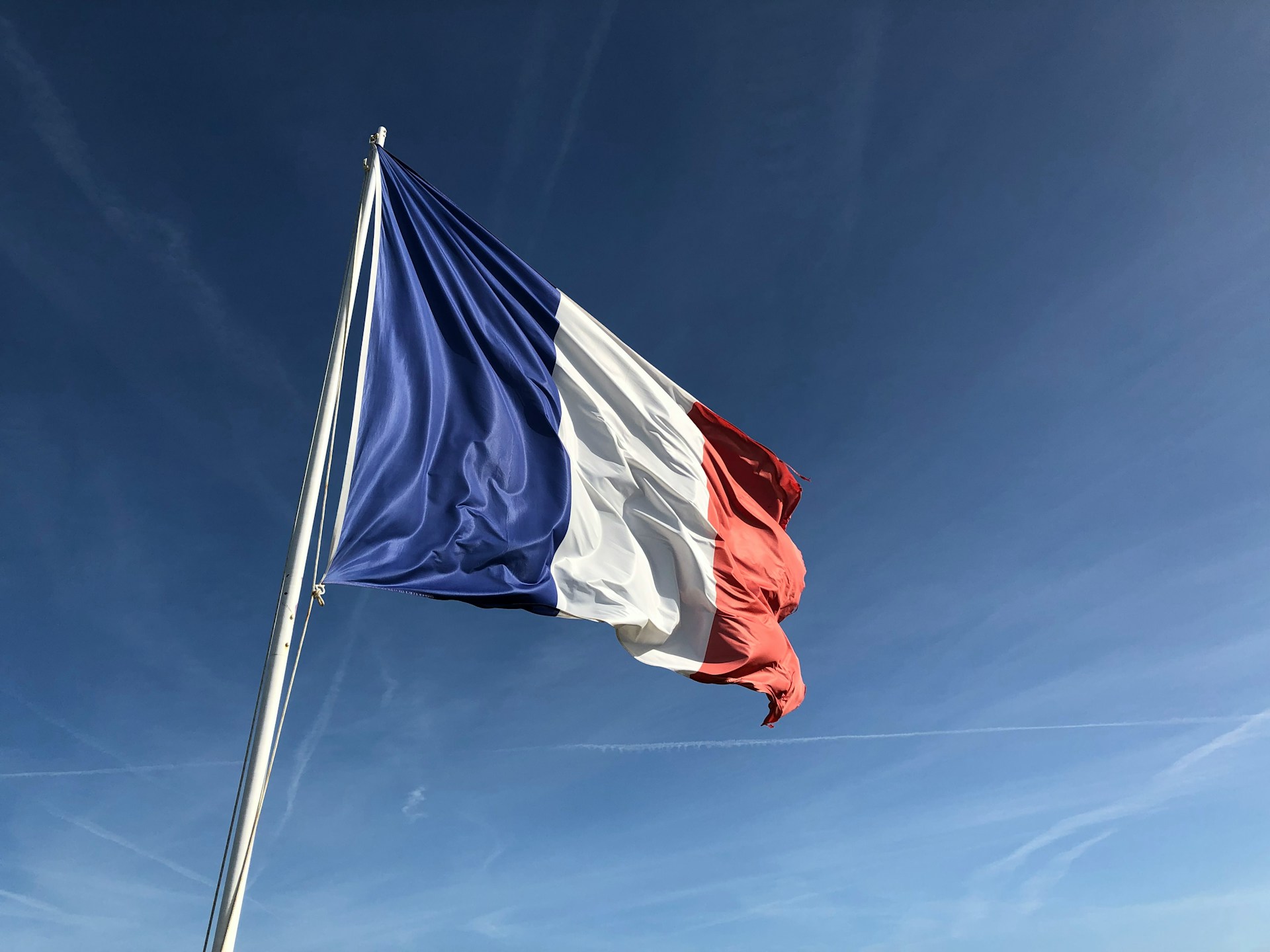 anthony-choren-lYzap0eubDY-unsplash Frankreich Flagge vor blauem Himmel