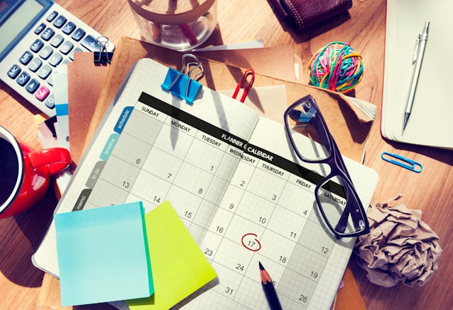 Curated Lifestyle via Unsplash Calender, post its and glasses on a messy desk