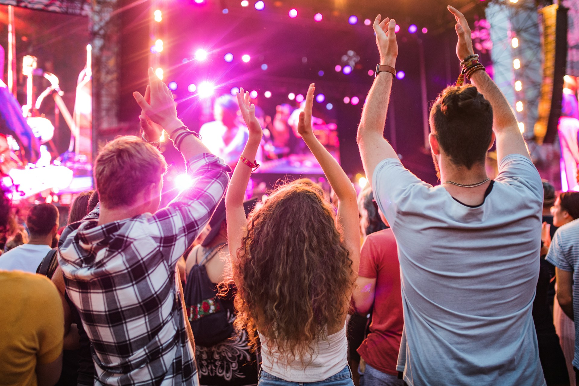 Drei Personen von hinten tanzend auf Festival