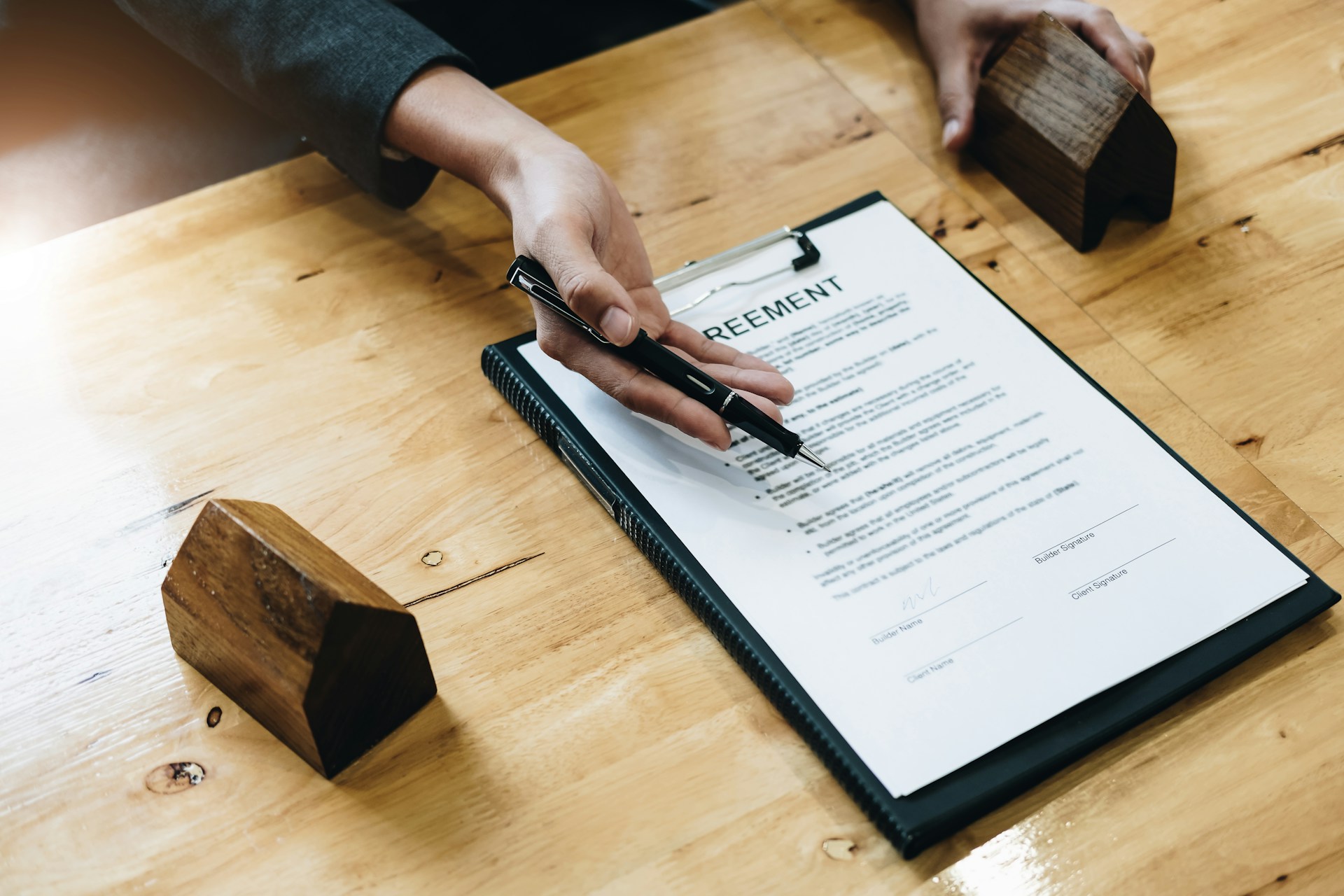 Property agreement document with house models on a desk representing holiday rental legal requirements in Spain"