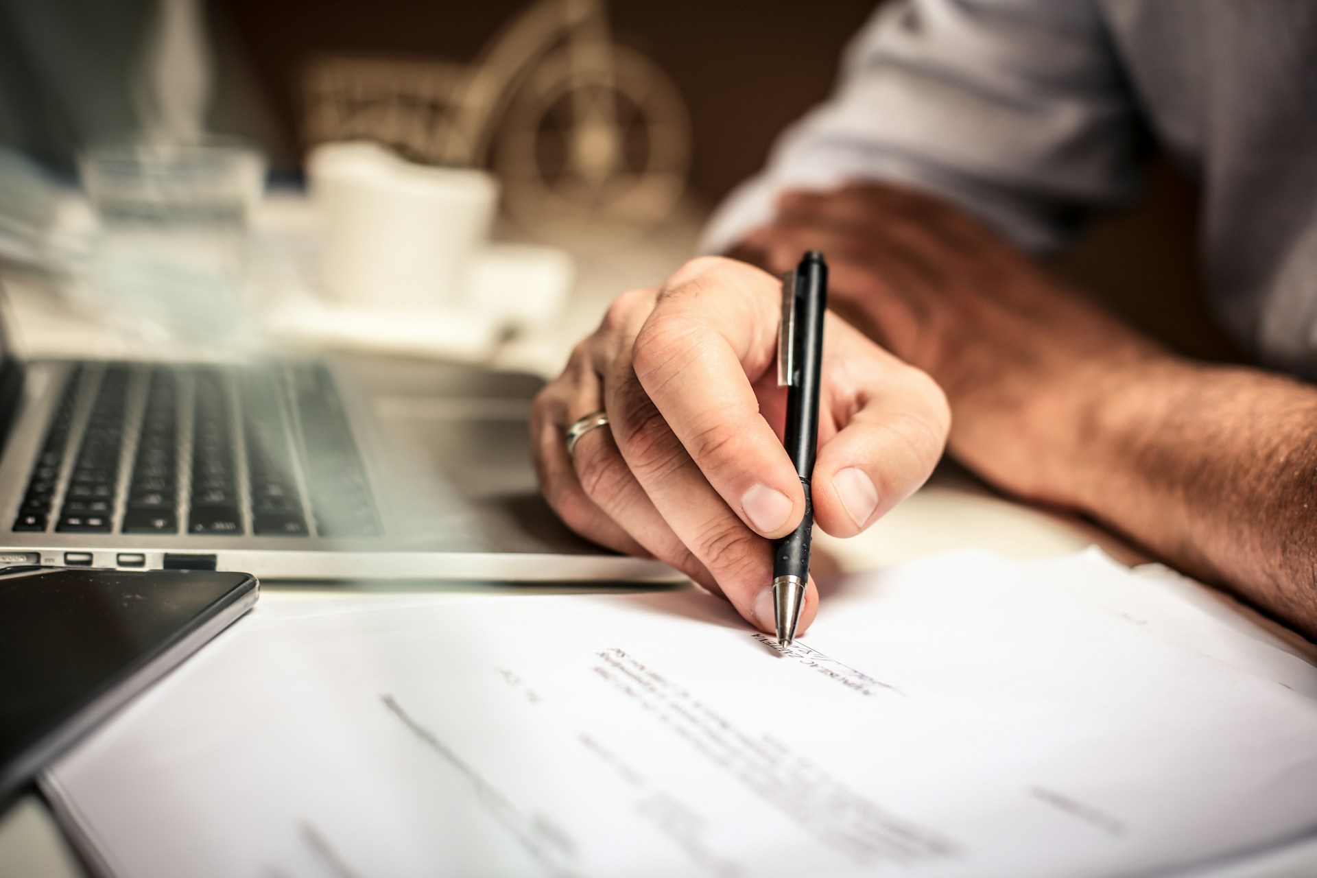Landlord signing a mid-term rental agreement document next to a laptop