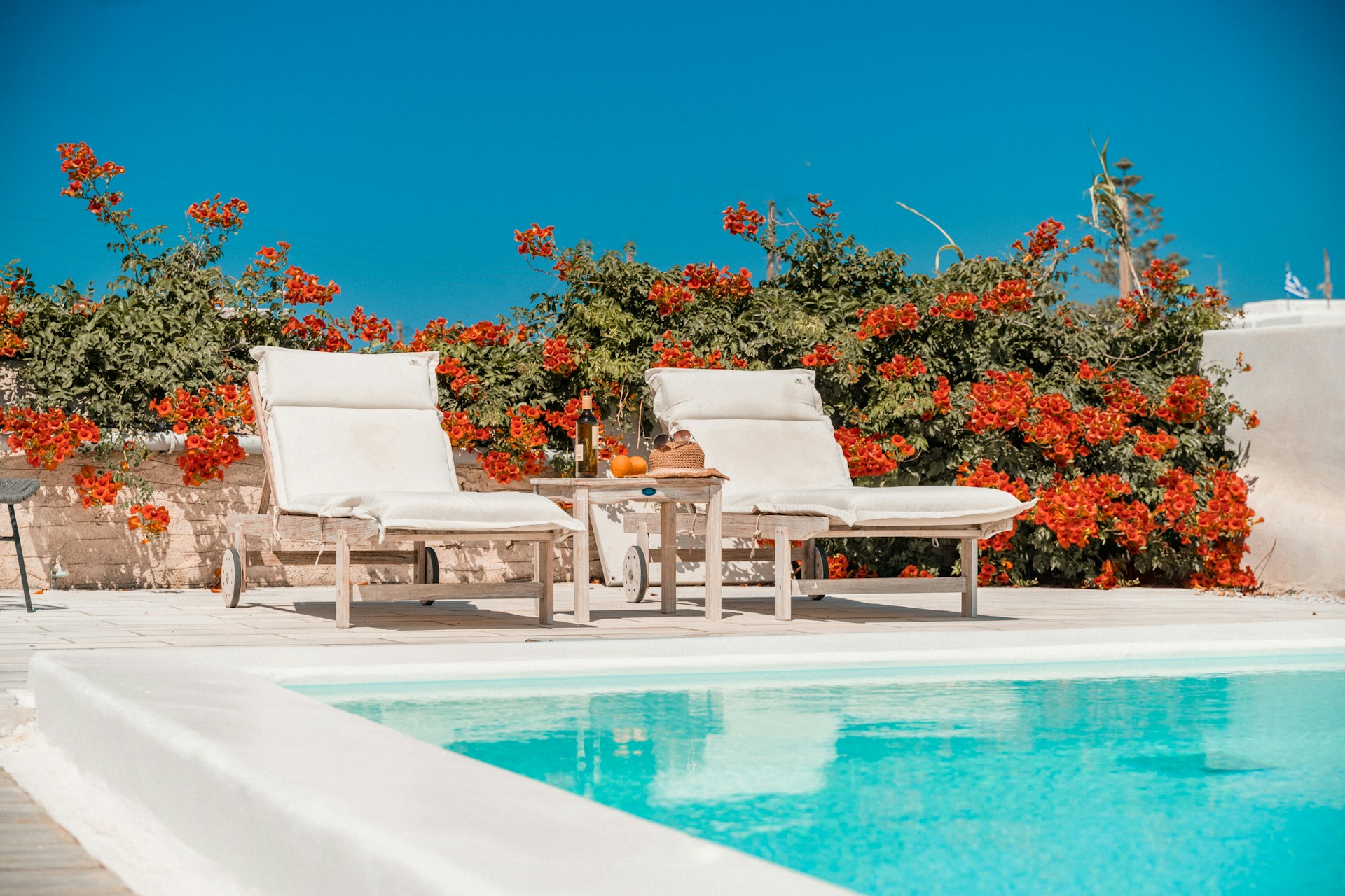 Luxury holiday rental pool with sun loungers and Mediterranean flowers representing premium features that justify higher prices in Spain