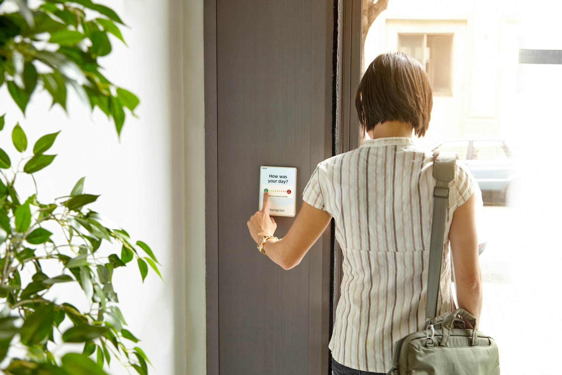 celpax via unsplash Person tippt im Vorbeigehen auf ein an der Wand montiertes Feedback-Terminal