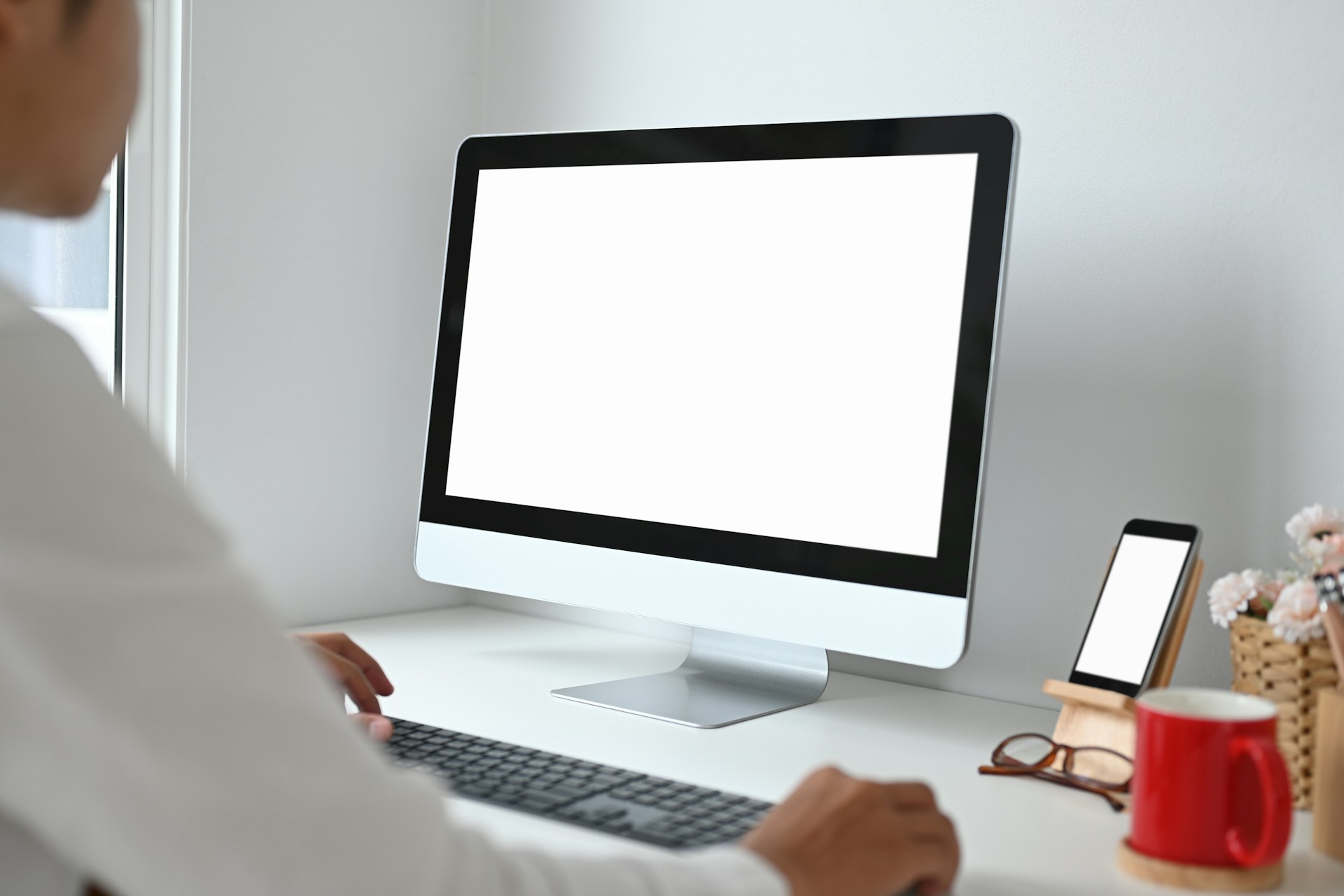 getty-images unsplash Person, die an einem Schreibtisch vor einem großen Computerbildschirm mit weißer Freifläche arbeitet