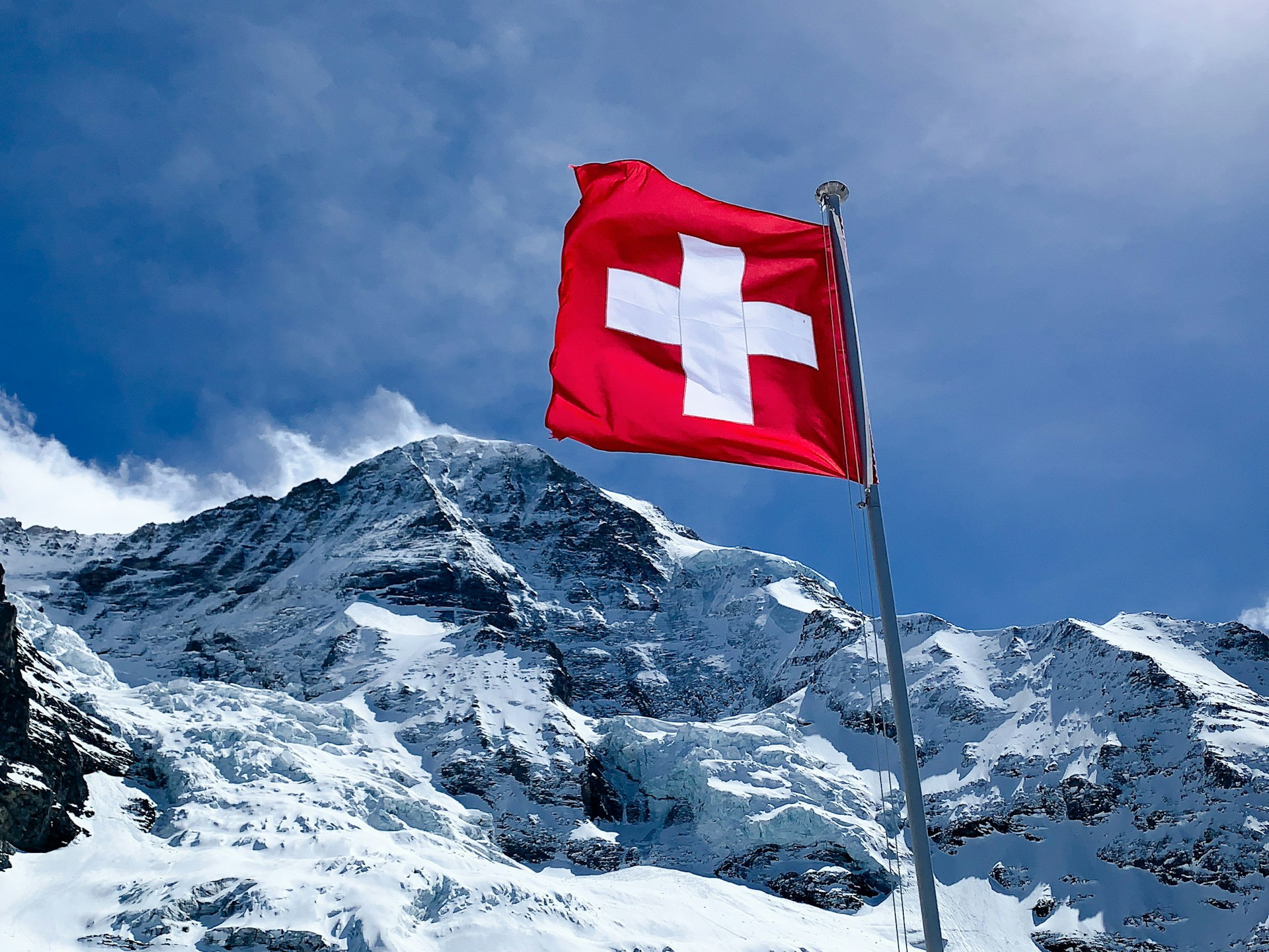 Schneebedeckter Berg und im Vordergrund eineSchweizer Flagge