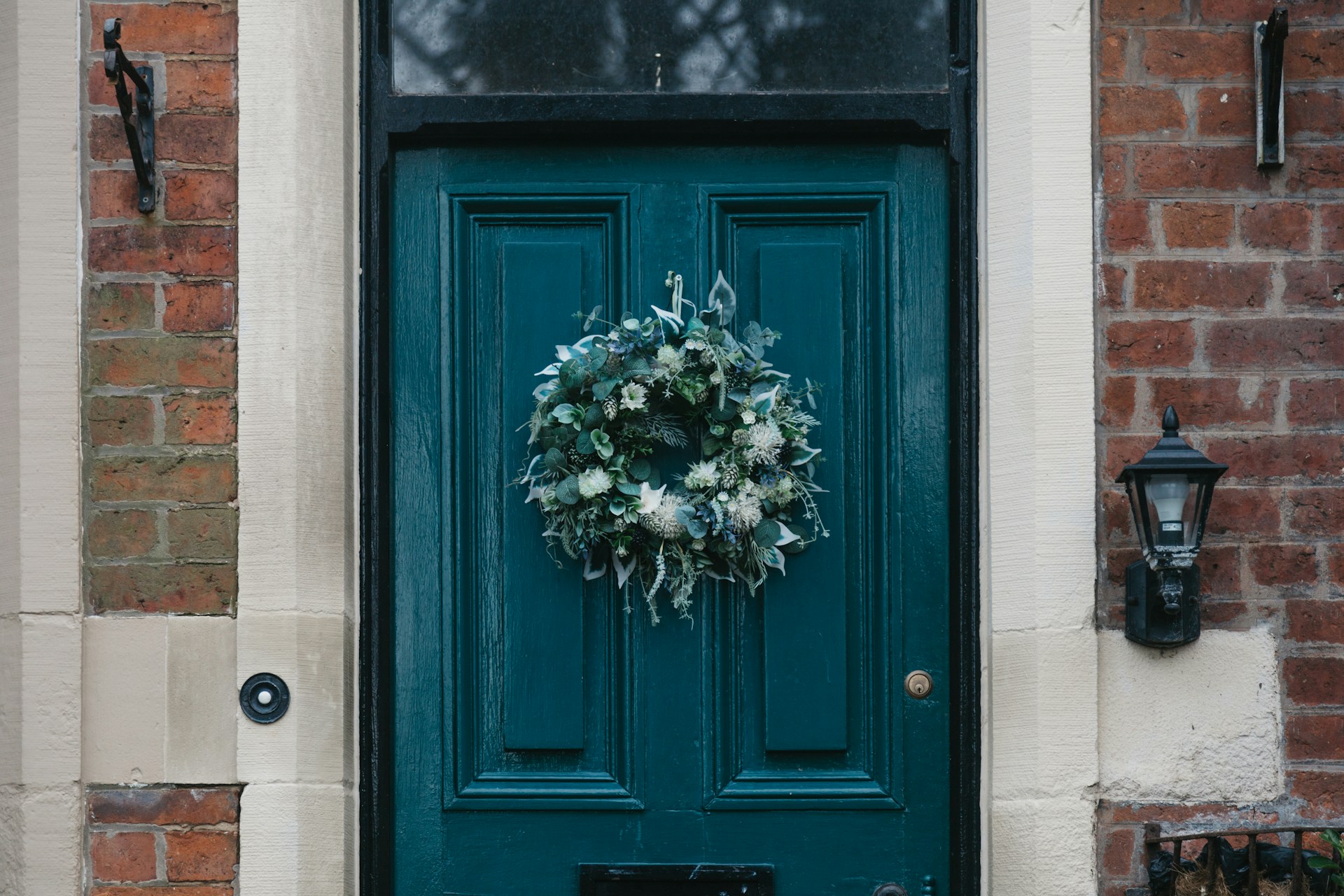 polina-oZTzM4_C_4s-unsplash Elegant Christmas wreath hanging on a teal front door of a brick home