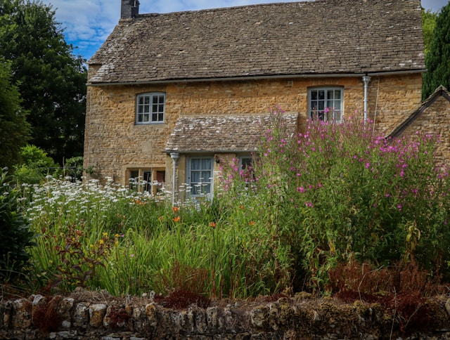 martin-fenton-CUGep7Df0hM-unsplash (1) Charming countryside stone cottage with a slate roof and a vibrant wildflower garden behind a drystone wall