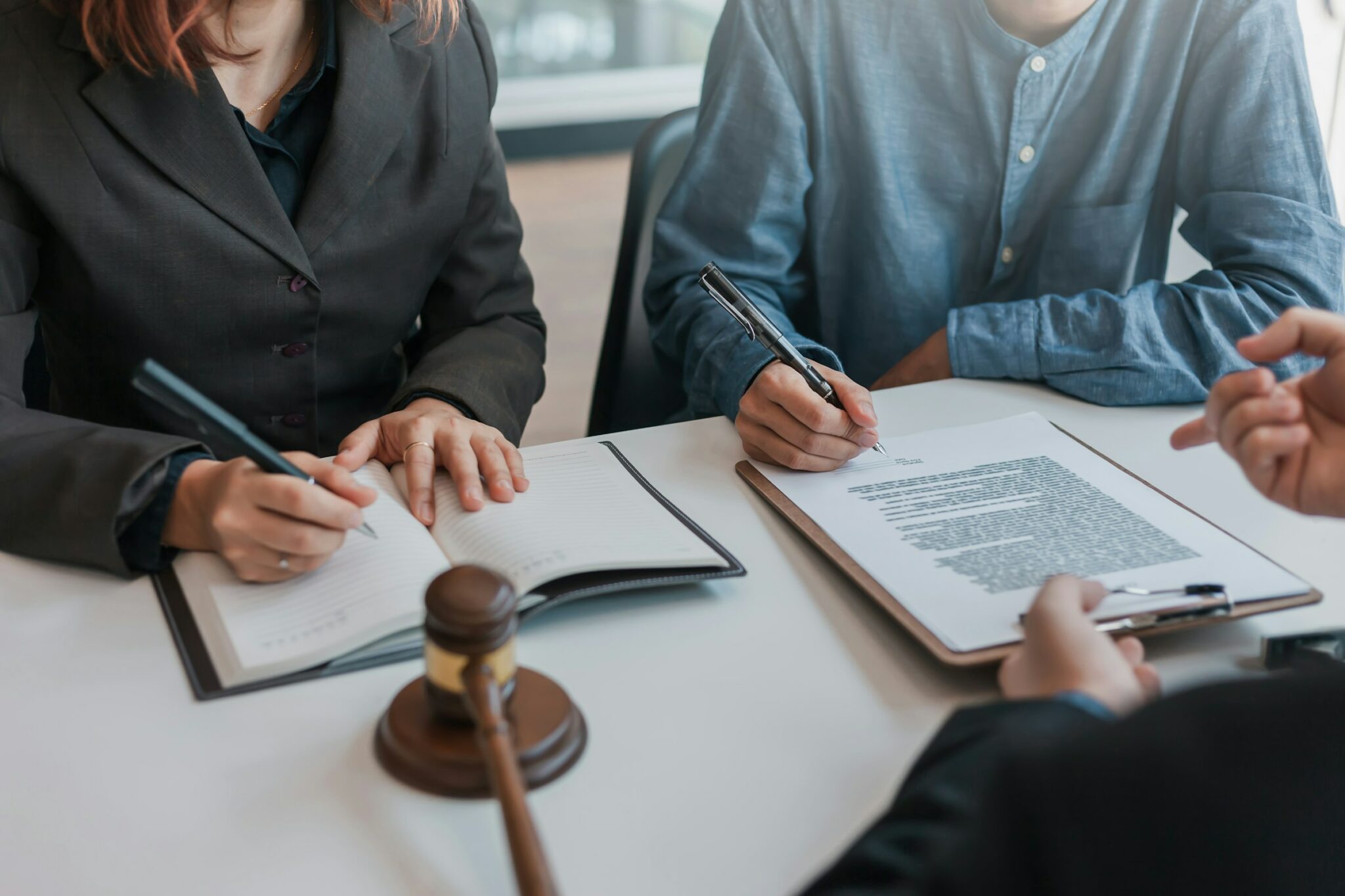 getty-images-sylnbYho0Vs-unsplash zwei Personen unterzeichnen Verträge, neben Richterhammer