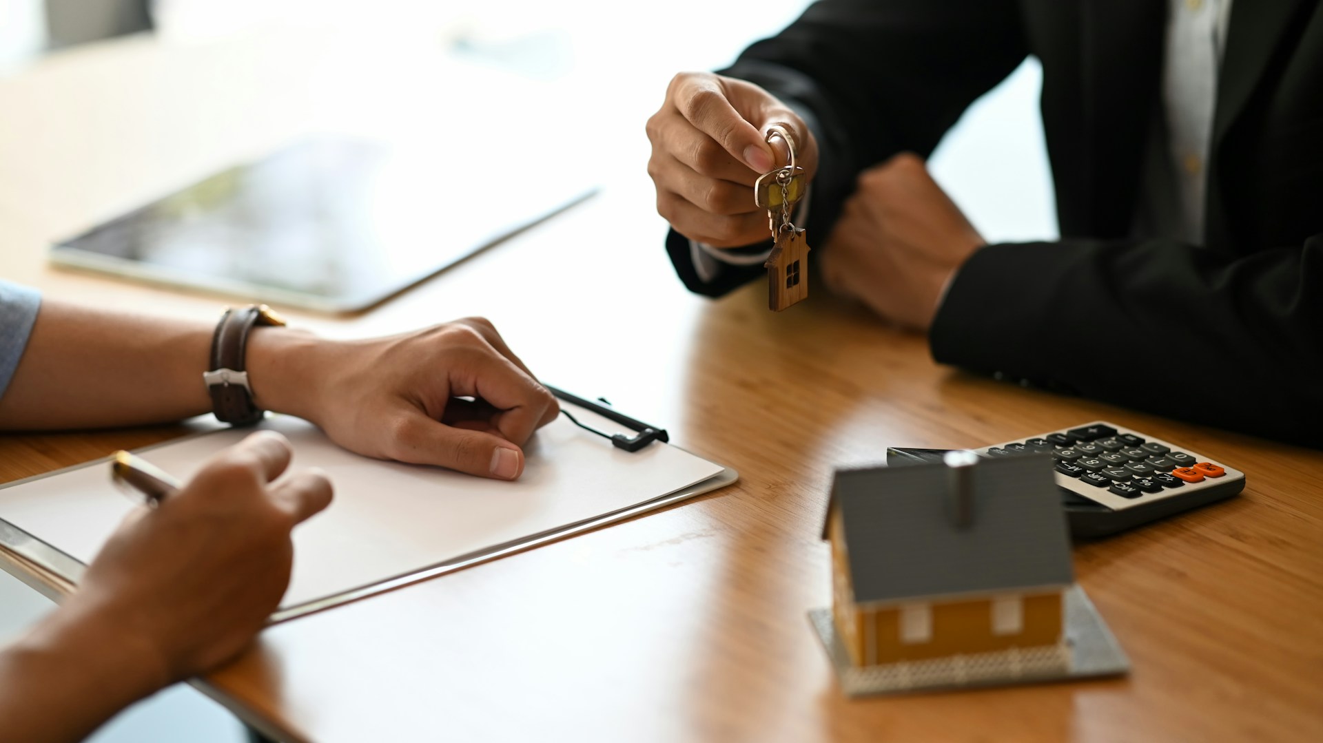 Heriter d'une maison, une main donne les clés a une autre personne qui signe les papiers