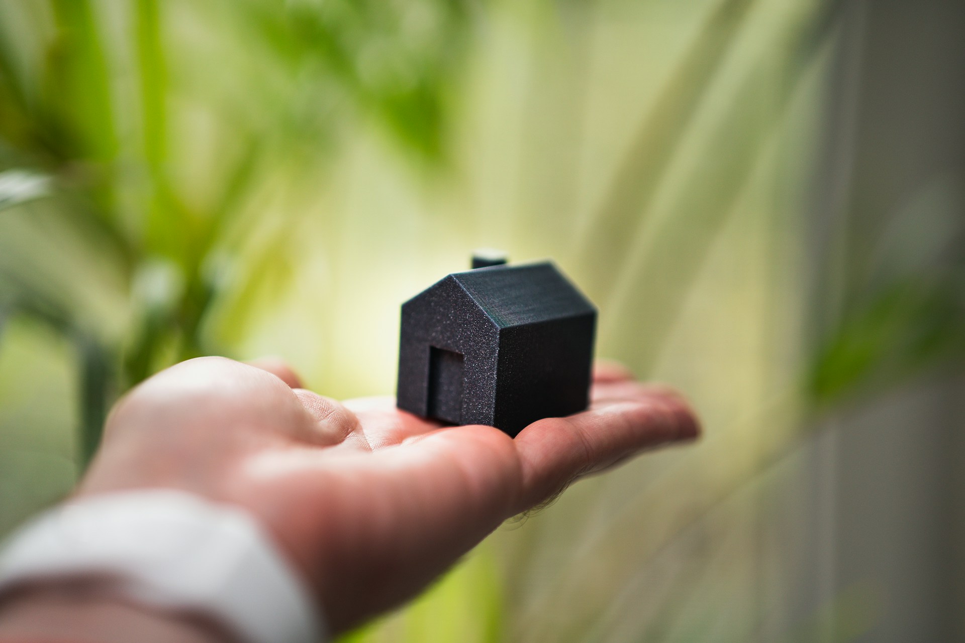 Jakub Żerdzicki auf Unsplash Man hält Haus in seinen Händen