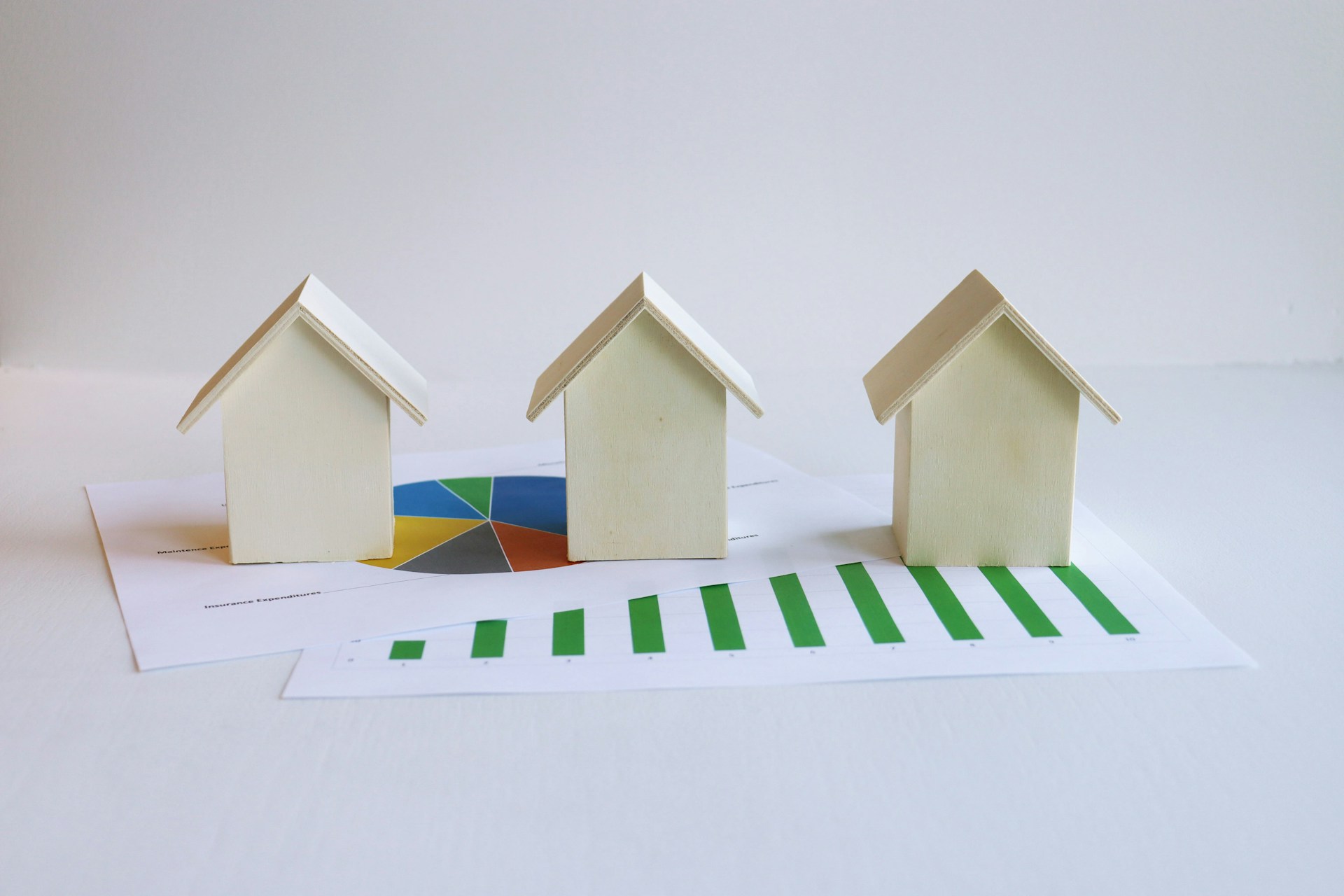 How to scale your short-term rental business Three wooden houses sat on some printouts of charts