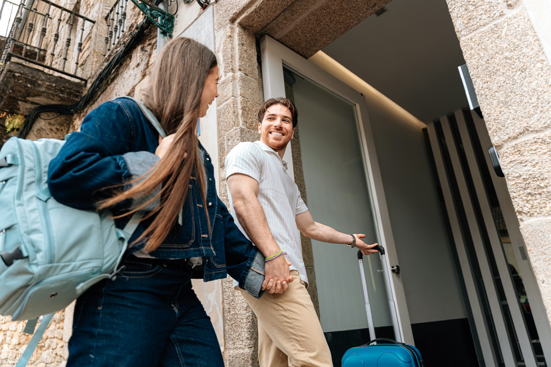 a-c-sAMum4zpu_k-unsplash Smiling couple arriving at a holiday rental door in a European stone-built street, with luggage