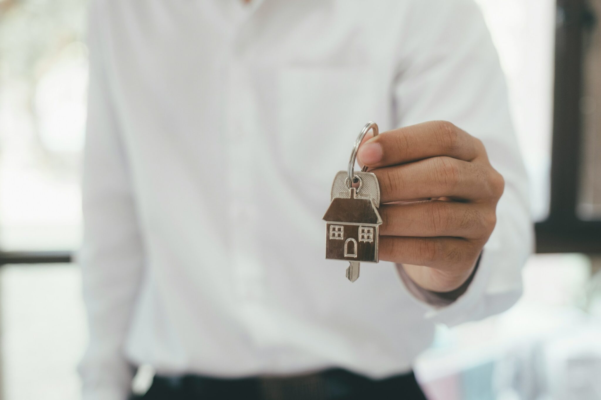 getty-images-pWZsKeguGyw-unsplash Mann übergibt Schlüssel mit Haus-Anhänger